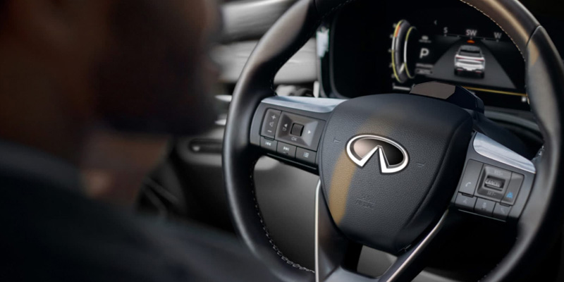 Close-up of INFINITI steering wheel with driver in background